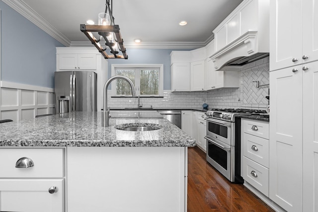 kitchen featuring appliances with stainless steel finishes, a sink, a kitchen island with sink, and white cabinets