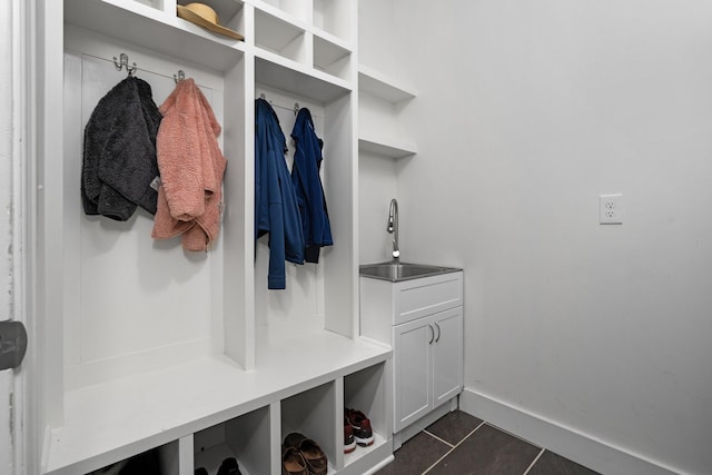 mudroom with dark tile patterned flooring, a sink, and baseboards