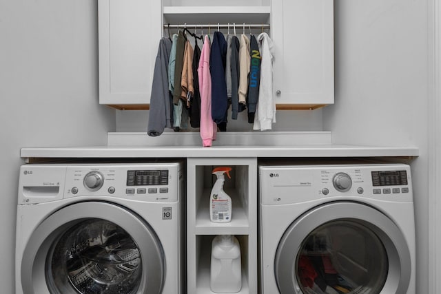 clothes washing area with washing machine and dryer and cabinet space