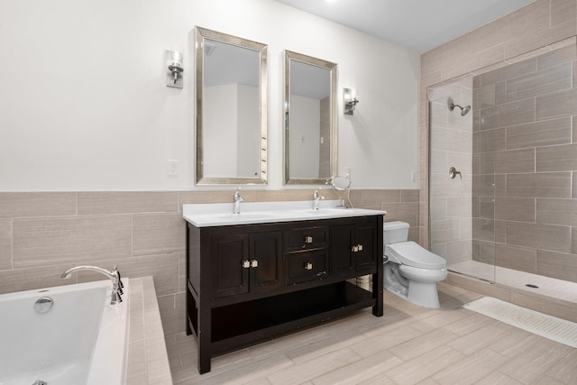 full bath featuring tile walls, double vanity, toilet, wainscoting, and a bath