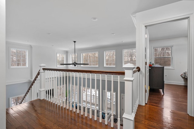 corridor featuring dark wood-style floors, baseboards, and an upstairs landing