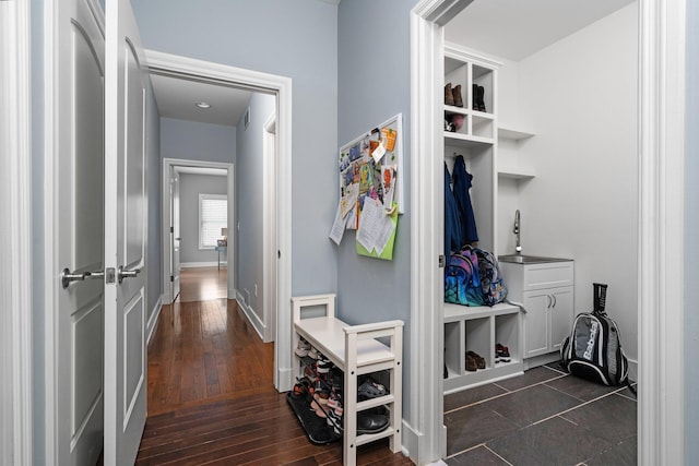 mudroom featuring dark wood-style flooring, a sink, visible vents, and baseboards