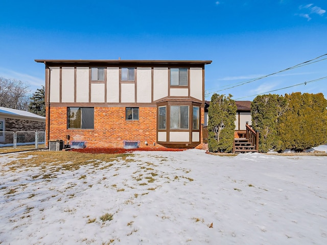 snow covered rear of property with brick siding and central air condition unit