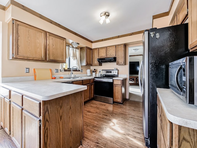 kitchen with under cabinet range hood, stainless steel appliances, a peninsula, a sink, and light countertops