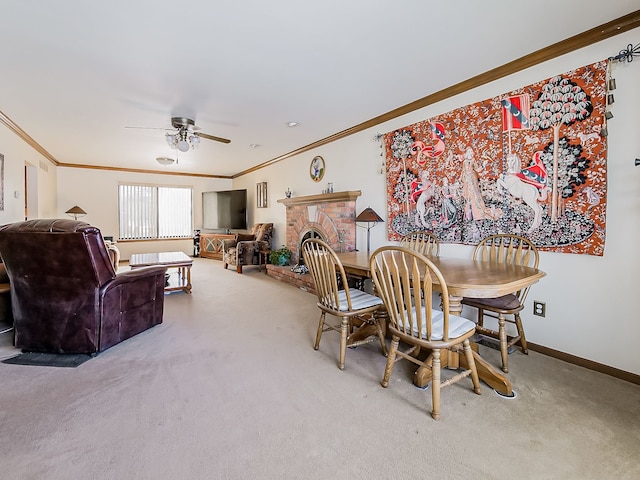 carpeted dining area with ceiling fan, a fireplace, baseboards, and ornamental molding