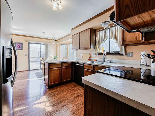 kitchen featuring light countertops, a sink, dishwasher, a peninsula, and stainless steel fridge with ice dispenser