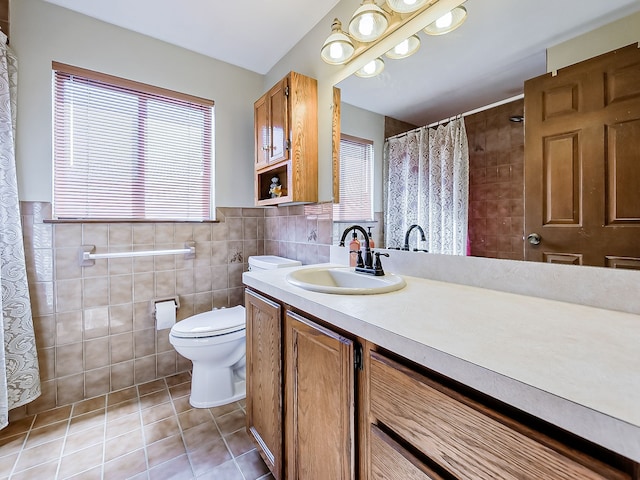 full bathroom with toilet, a wainscoted wall, tile patterned flooring, vanity, and tile walls