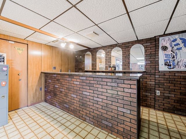 bar with a paneled ceiling, brick wall, and bar