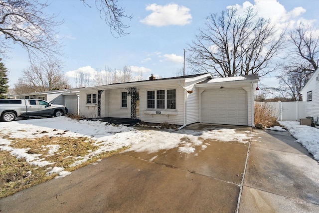 ranch-style home featuring a garage, driveway, and fence