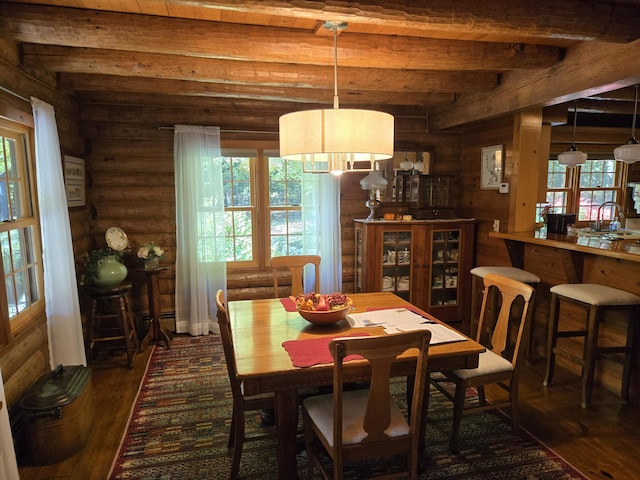 dining room featuring rustic walls, dark wood-style floors, a wealth of natural light, and beam ceiling