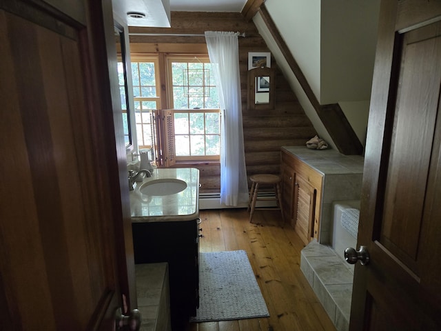 bathroom featuring baseboard heating, rustic walls, vanity, and hardwood / wood-style floors