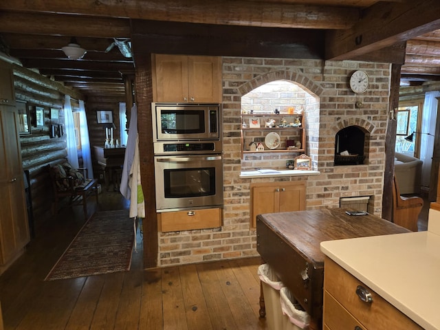 kitchen featuring beam ceiling, rustic walls, light countertops, appliances with stainless steel finishes, and hardwood / wood-style floors