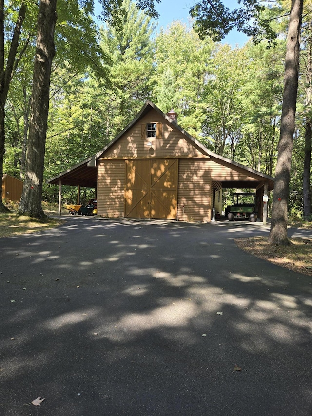 view of side of property featuring an outbuilding, aphalt driveway, and a chimney