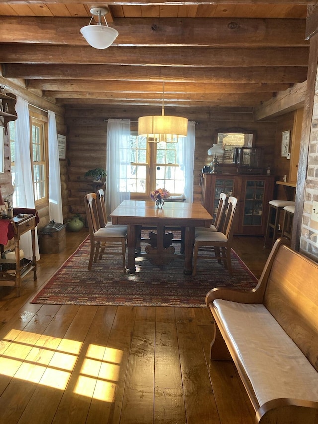 dining space featuring rustic walls, plenty of natural light, beamed ceiling, and hardwood / wood-style flooring