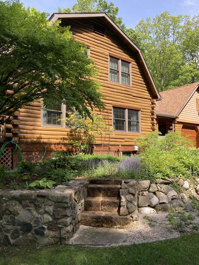 view of home's exterior with a gambrel roof and log siding