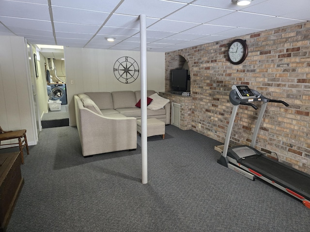 workout room featuring washer / dryer, a paneled ceiling, brick wall, and carpet