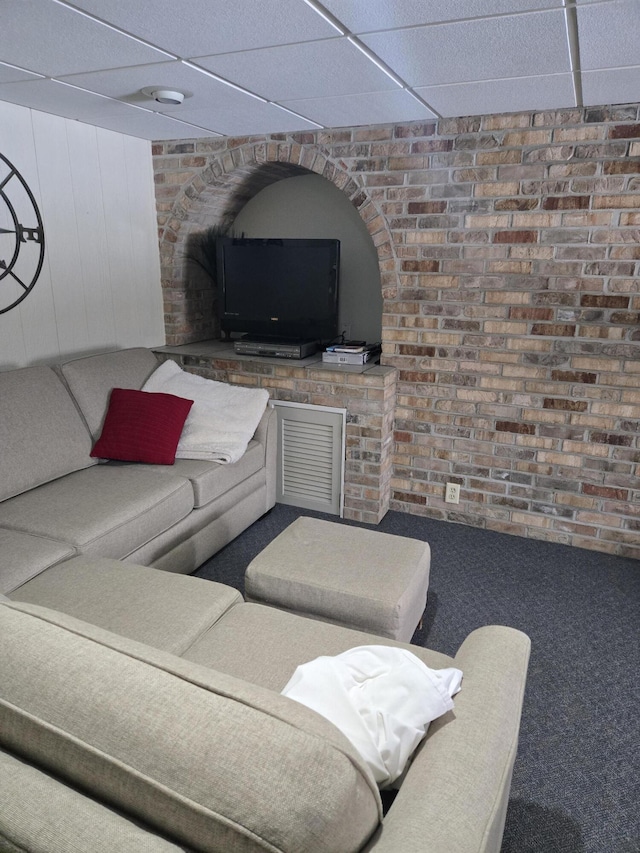 living room with brick wall, visible vents, and a drop ceiling