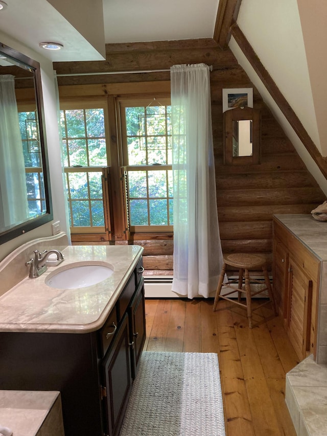 bathroom featuring hardwood / wood-style floors, vanity, and log walls