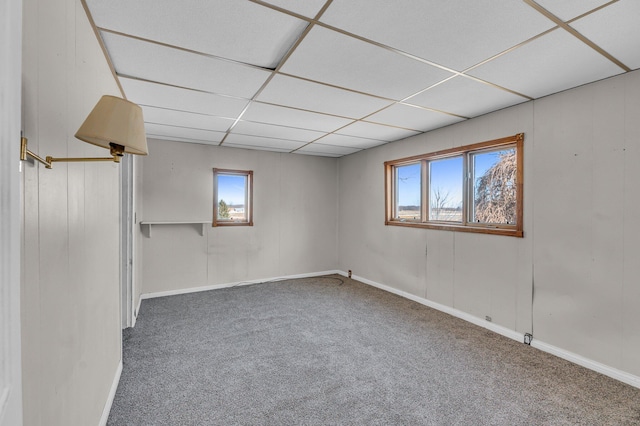 spare room featuring a drop ceiling, carpet flooring, and baseboards