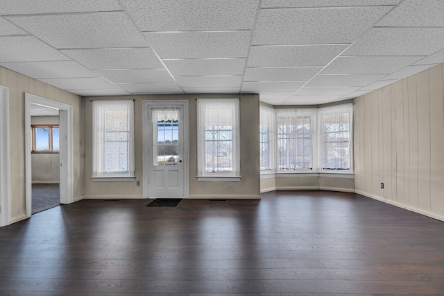 spare room featuring a healthy amount of sunlight, dark wood-style floors, and a paneled ceiling