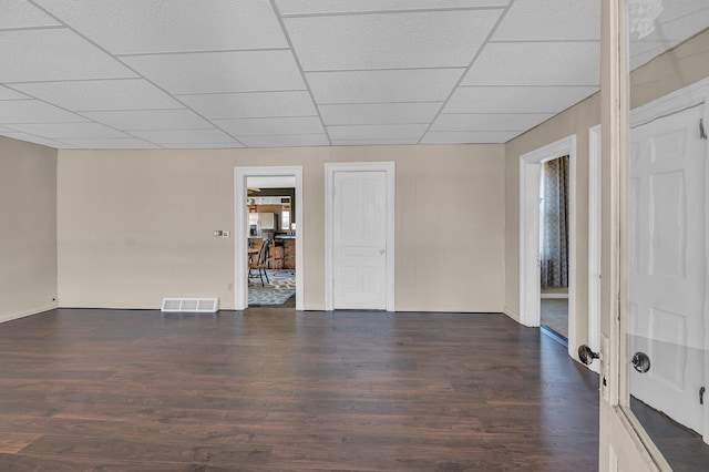 unfurnished room with dark wood-style floors, baseboards, visible vents, and a drop ceiling