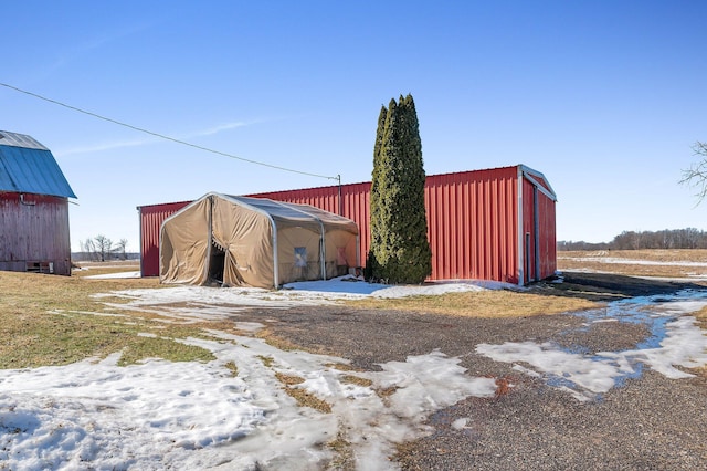 snow covered structure with an outbuilding