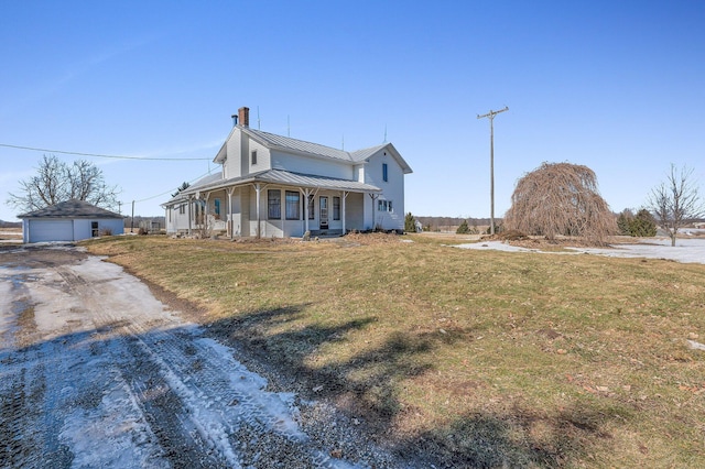 farmhouse featuring metal roof, a porch, a garage, an outdoor structure, and a standing seam roof