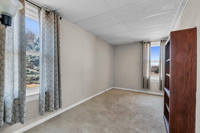 spare room featuring carpet flooring, a wealth of natural light, and baseboards