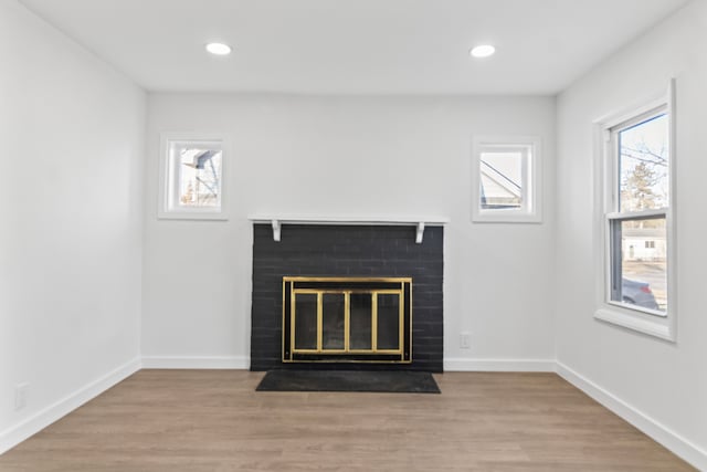 unfurnished living room featuring a brick fireplace, baseboards, wood finished floors, and recessed lighting