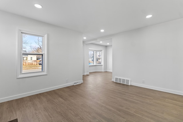 empty room with wood finished floors, visible vents, and recessed lighting