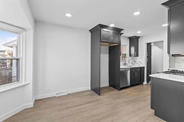 kitchen with visible vents, dishwasher, light countertops, light wood-type flooring, and a sink