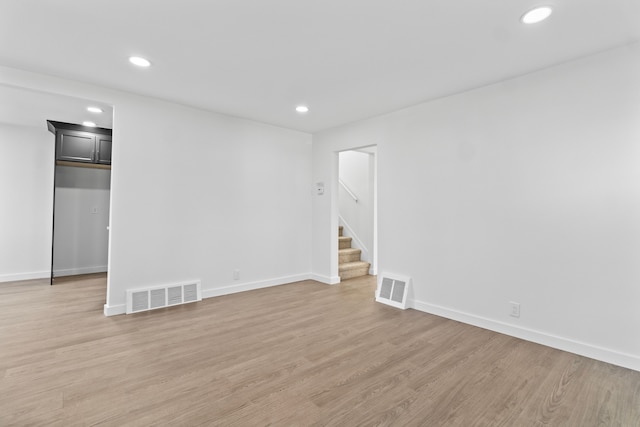 empty room with recessed lighting, visible vents, light wood finished floors, and stairs