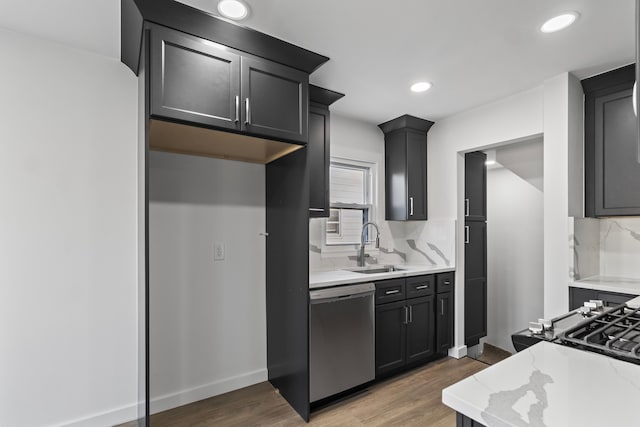 kitchen featuring a sink, light wood finished floors, decorative backsplash, and stainless steel dishwasher