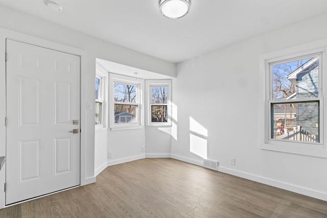 foyer entrance featuring baseboards, visible vents, and wood finished floors