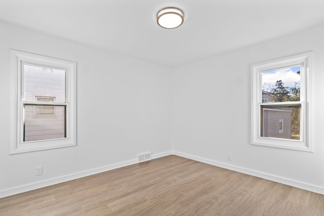 empty room with baseboards, visible vents, and wood finished floors