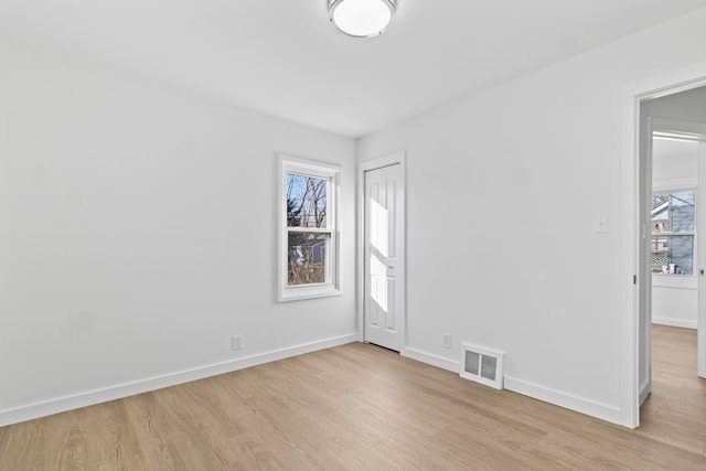 unfurnished room with light wood-style floors, visible vents, and baseboards