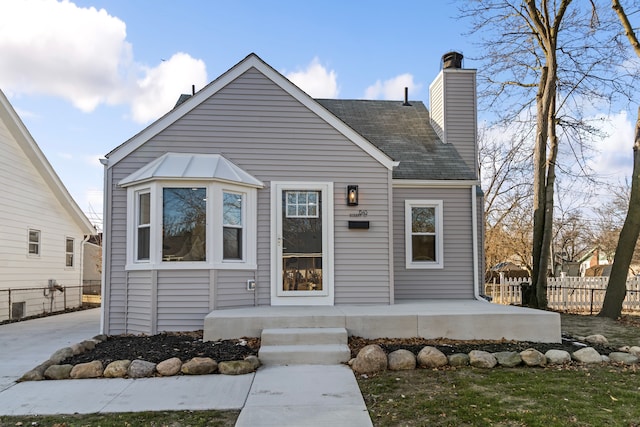 view of front of property with a chimney, fence, and roof with shingles