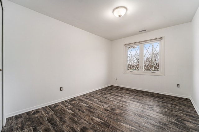 unfurnished room featuring dark wood finished floors, visible vents, and baseboards