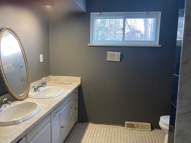 bathroom with toilet, visible vents, a sink, and tile patterned floors