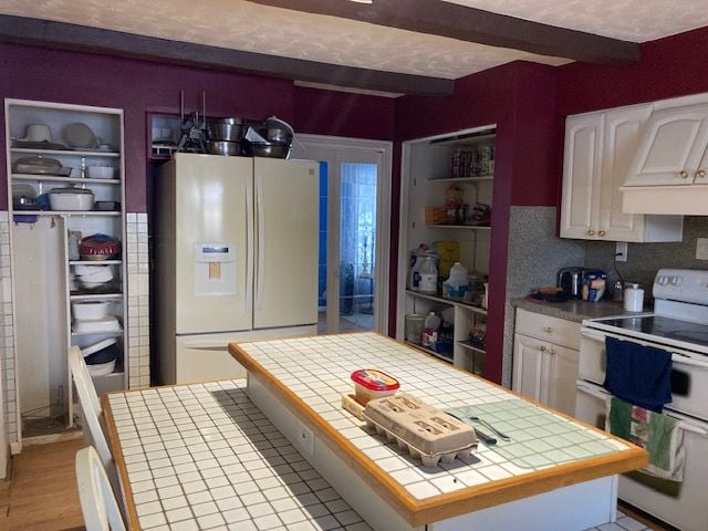 kitchen featuring tile countertops, white appliances, beam ceiling, and white cabinetry