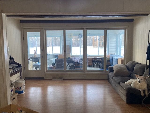 living room with visible vents, wooden walls, and wood finished floors