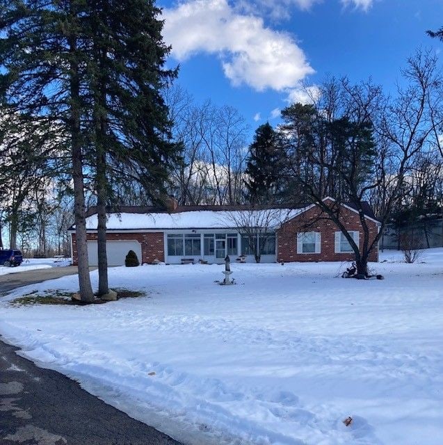 ranch-style home with a sunroom, brick siding, and an attached garage