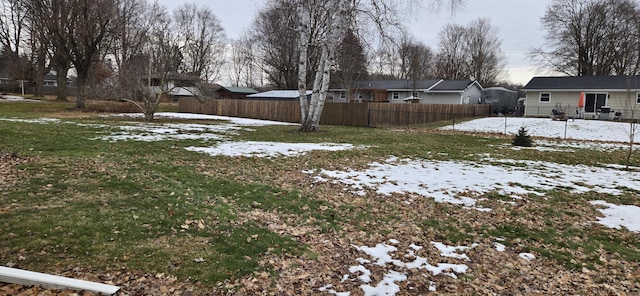 snowy yard with a residential view and fence