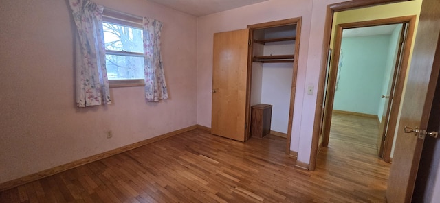 unfurnished bedroom with light wood-type flooring, a closet, and baseboards