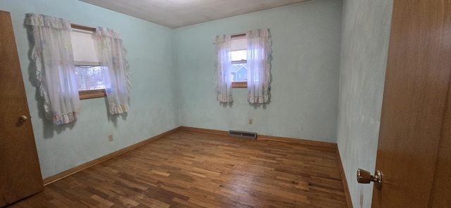 empty room featuring visible vents, baseboards, and wood finished floors