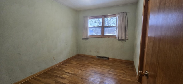 unfurnished room featuring visible vents, baseboards, and wood finished floors