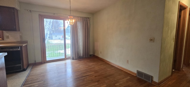 unfurnished dining area with a notable chandelier, wood finished floors, visible vents, and baseboards