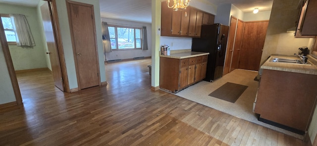 kitchen featuring black fridge, light wood-style flooring, light countertops, and a sink