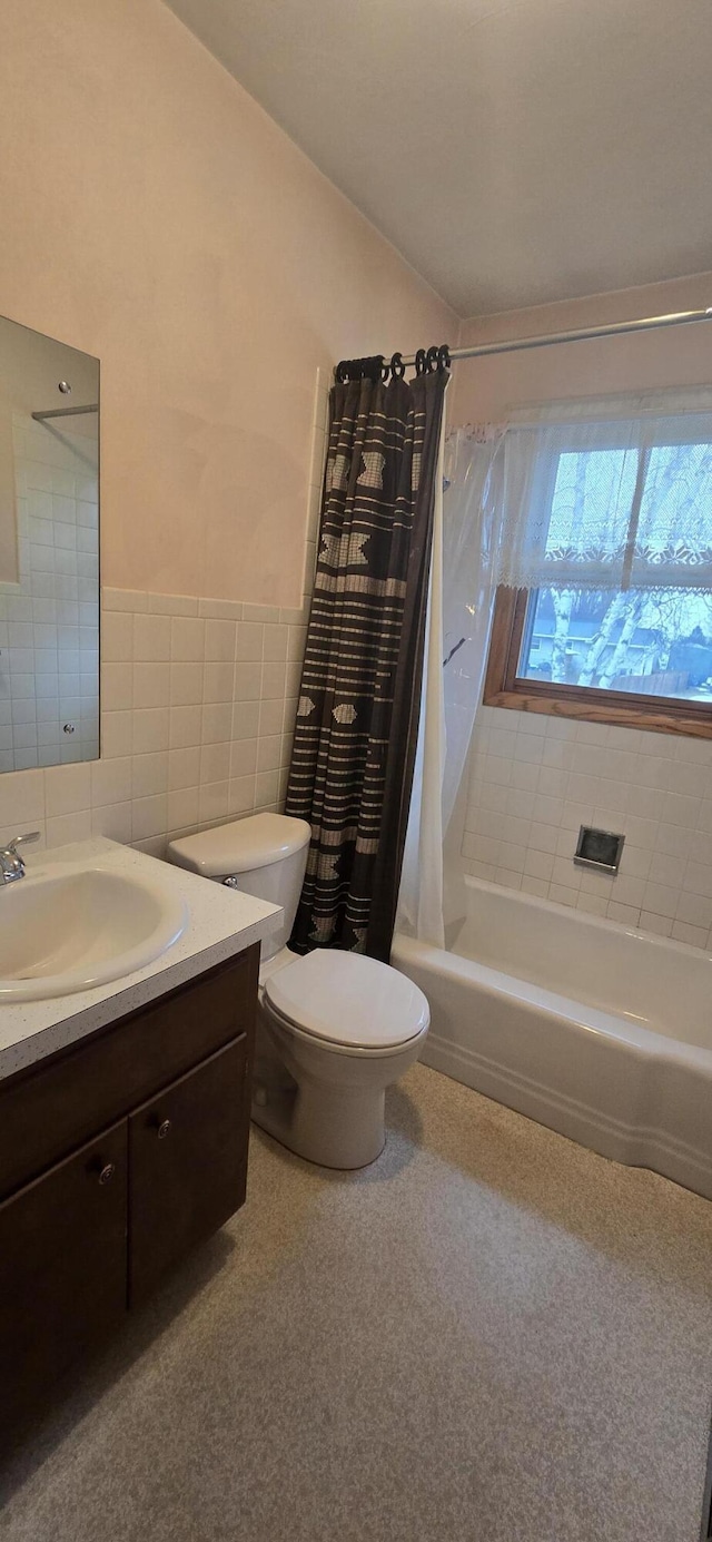 bathroom with tile walls, toilet, shower / bath combo with shower curtain, wainscoting, and vanity