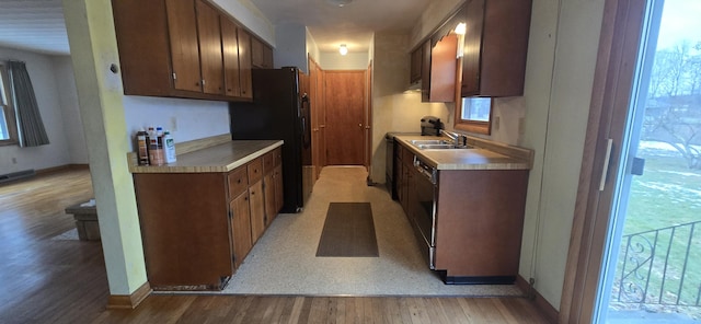 kitchen featuring a sink, black appliances, light countertops, and light wood finished floors